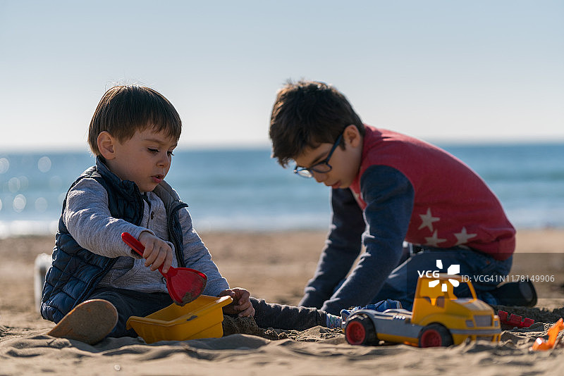 快乐男孩在海滩上玩玩具卡车图片素材