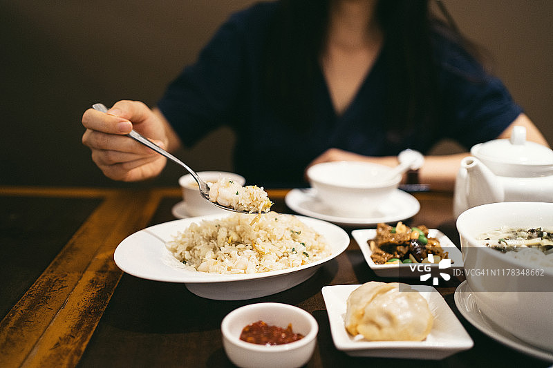 年轻的亚洲女人在中国餐馆里吃着炒饭和各种各样的菜图片素材