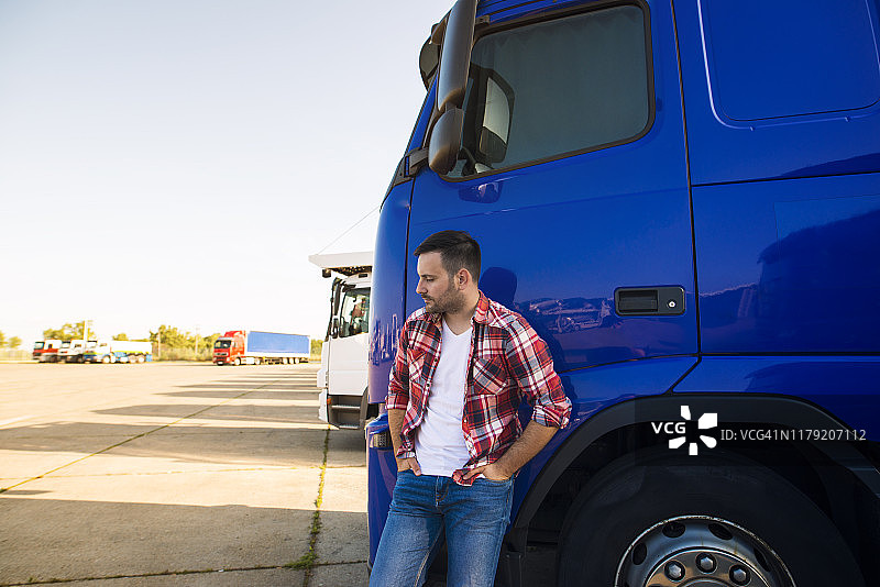 专业卡车司机站在他的卡车旁的肖像。运输服务。图片素材