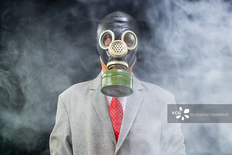 一个戴着防毒面具的男人在烟雾中。黑色背景图片素材