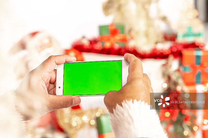 圣诞老人拿着有色度键的智能手机，上面有绿色屏幕，特写图片素材