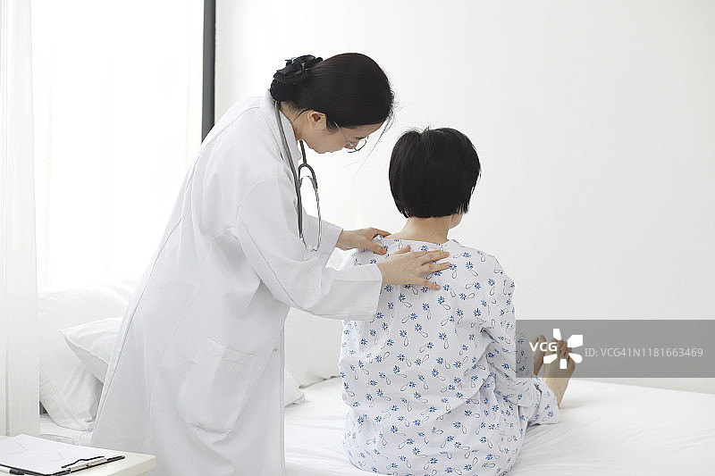 医生在病床上检查病人的肩膀图片素材