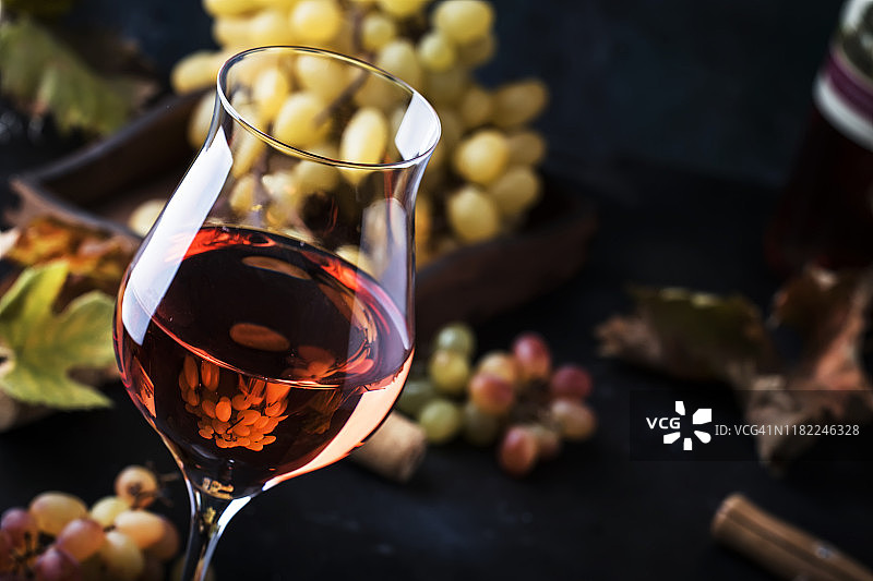 玫瑰葡萄酒的品酒概念。灰色背景，葡萄和叶子。酒杯里的粉红色葡萄酒。本空间图片素材