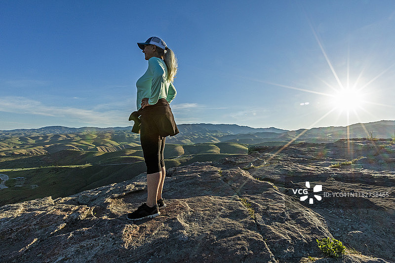 在美国爱达荷州的博伊西，一个成熟的女人站在日落的岩石上图片素材