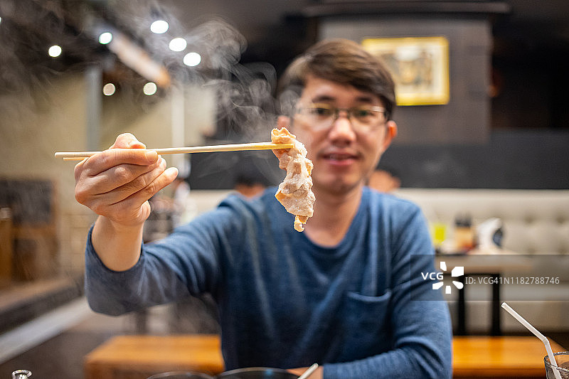 男人拿着筷子吃肉图片素材