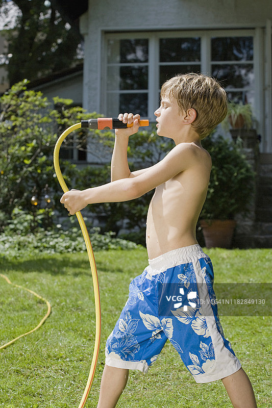 一个小男孩对着花园水管唱歌图片素材