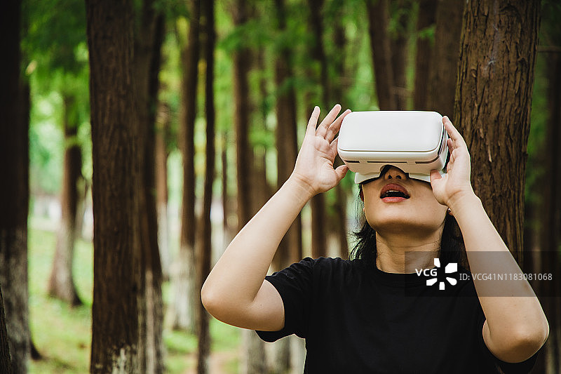 一个女人在森林中使用虚拟现实头盔图片素材