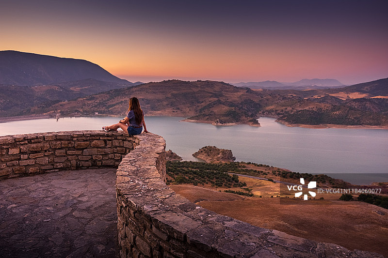 在西班牙的扎哈拉德拉塞拉，一名妇女在欣赏扎哈拉-埃尔加斯特水库的日落景色图片素材