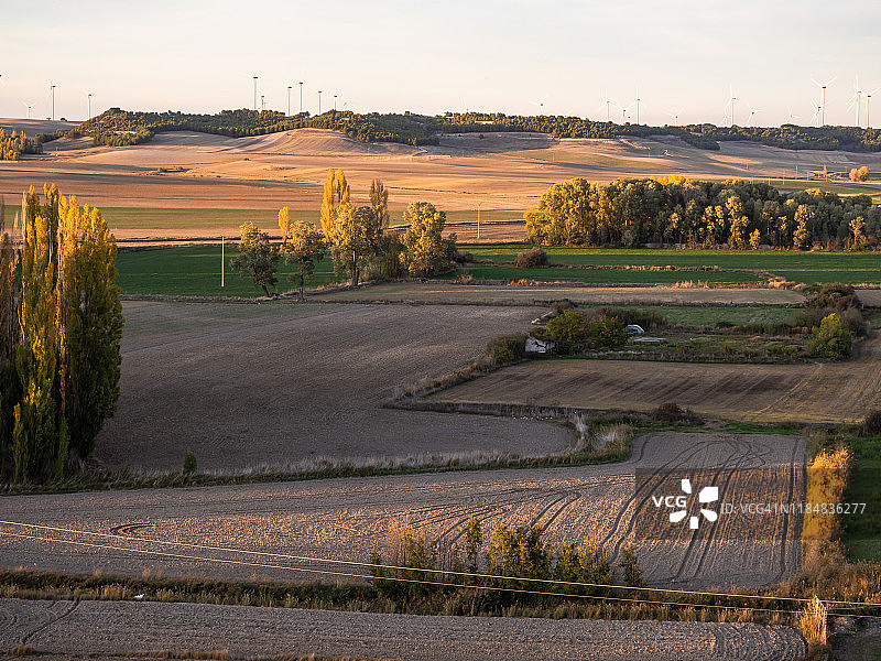 鸟瞰图与农场，农村道路，房屋和风力涡轮机地平线上西班牙市政Torrelobatón的秋天风景。图片素材