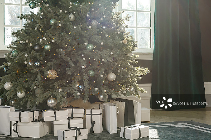 明亮的圣诞树和许多礼物靠近窗户图片素材