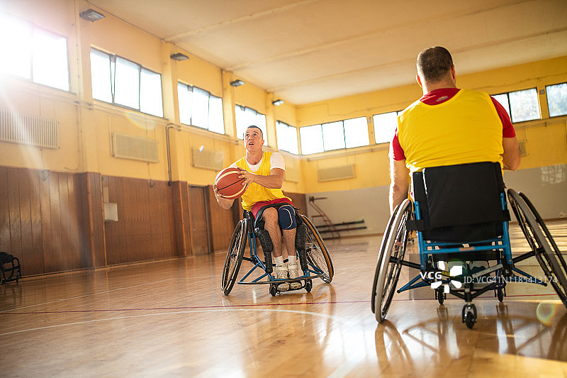 坐在轮椅上的男子在体育馆里打篮球图片素材
