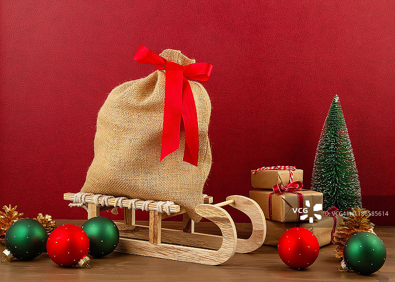 圣诞装饰木制的雪橇，松树，礼物与复制空间在红色的背景图片素材