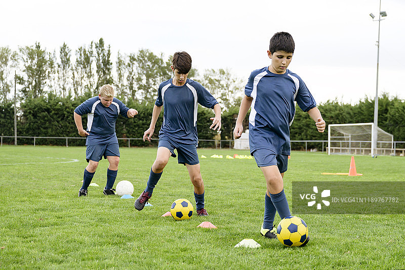 年轻的男性足球运动员在运动营练习运球图片素材