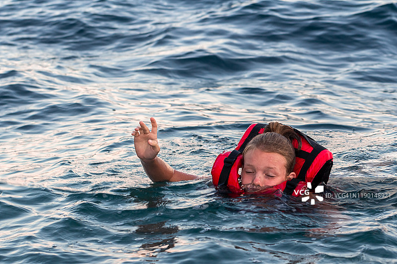 一名身穿红色救生衣的女孩在大海中惊恐地窒息而死图片素材