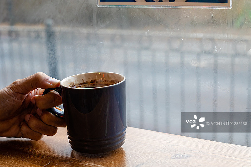 一个手拿着一杯咖啡在咖啡馆在寒冷的天气图片素材