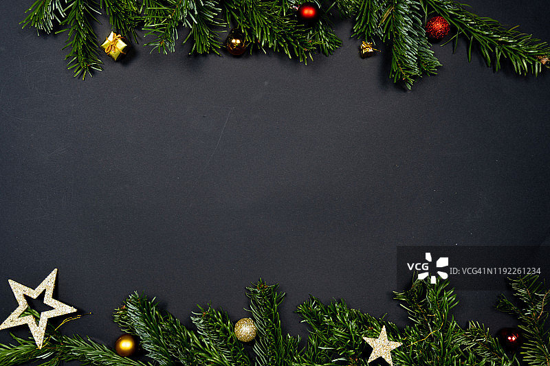 圣诞装饰品(圣诞装饰物，星星和小礼物)在黑色的背景框架下的冷杉树枝图片素材