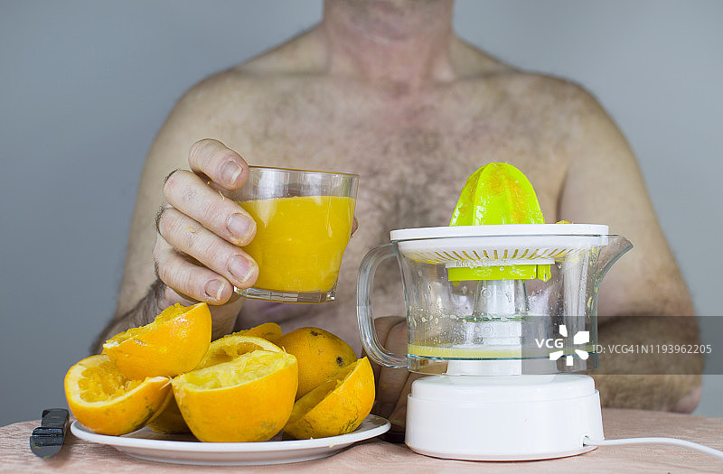 男人半裸着用榨汁机挤橘子图片素材