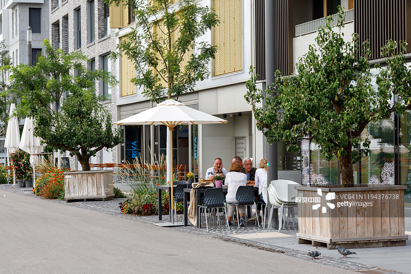 人们在房子附近的一个小咖啡馆里休息。现代城市空间结合了技术创新和景观基础设施。海尔布隆,图片素材