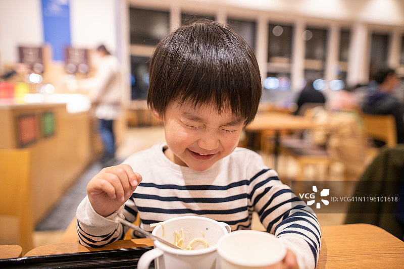 小男孩对美食广场的美味拉面很满意图片素材