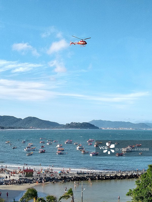 一架载有船只的救援直升机飞过海滩图片素材