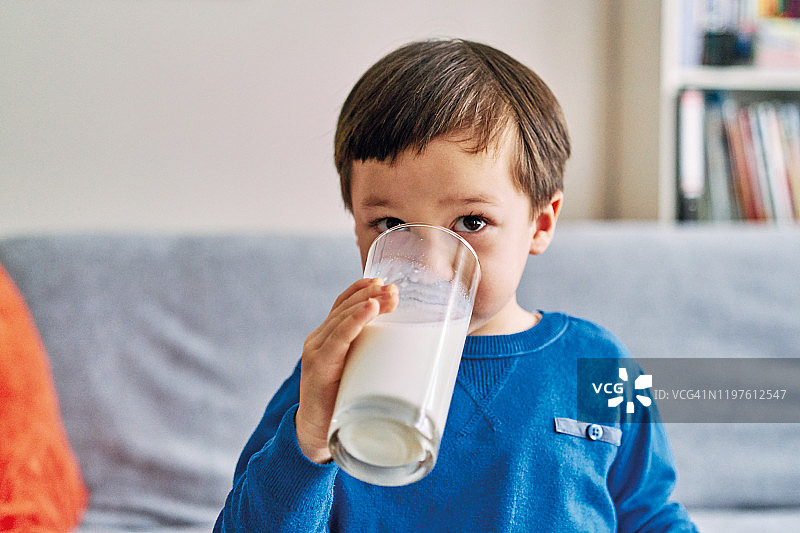 2-3岁可爱的孩子喝牛奶吃蛋糕。他喜欢牛奶。图片素材