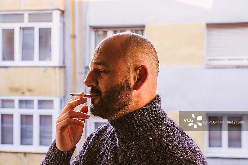 中年男子在建筑物旁吸烟图片素材