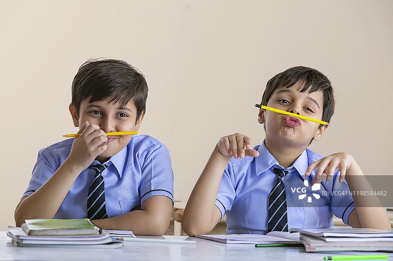 两个男孩在课堂上玩铅笔图片素材