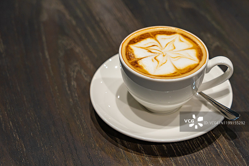 隔离美丽的卡布奇诺牛奶泡沫艺术咖啡在木桌上图片素材