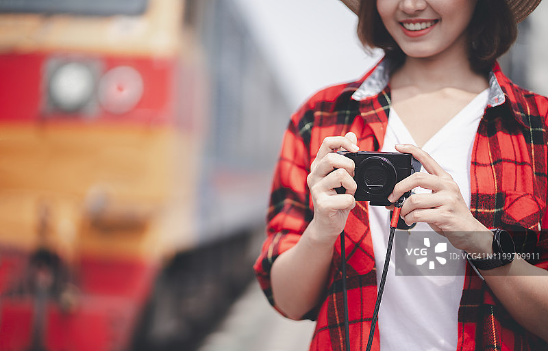 女摄影师正在用相机拍照。女游客以铁路为背景拍照。年轻的亚洲女性旅行者背包在城市。旅游的概念图片素材