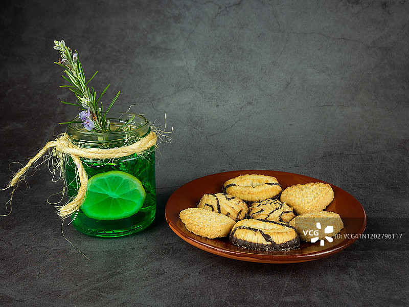绿色的百里香，迷迭香和柠檬浸泡在一个乡村的玻璃杯和茶糊在深灰色的背景图片素材