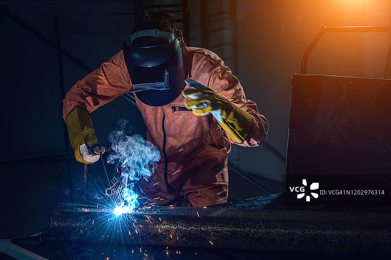工人在工业中使用安全面罩、安全手套和安全设备焊接钢材。工人焊接的概念。图片素材
