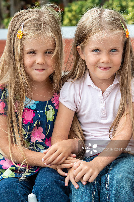 小女孩们手牵着手坐在一起图片素材