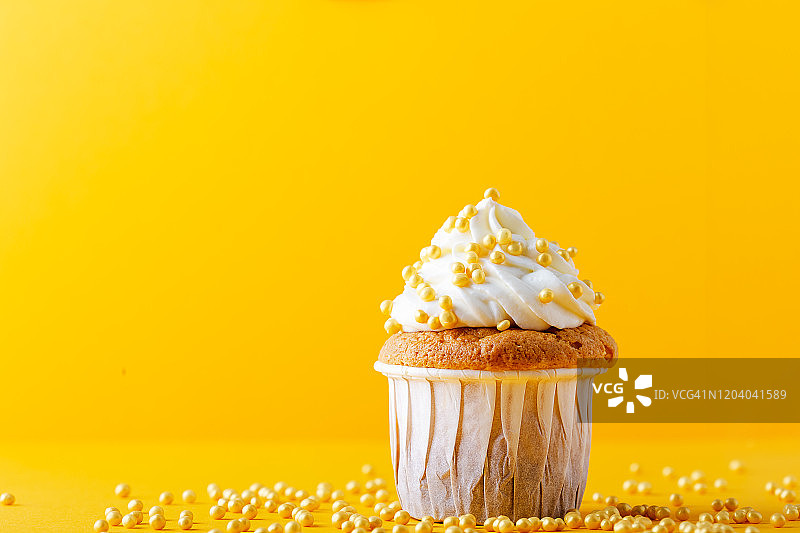 庆祝美食，一个黄色背景上撒有糖屑的小蛋糕图片素材