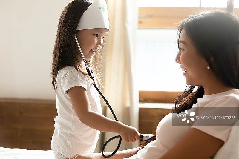 亚洲小女孩在年轻妈妈面前扮医生图片素材
