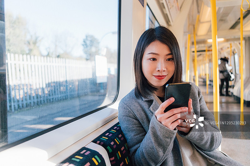 年轻女子在火车上使用智能手机图片素材
