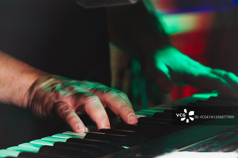 一个摇滚乐队的钢琴家或键盘手的手近距离演奏合成器图片素材
