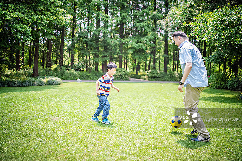 爸爸和儿子在公园里踢足球图片素材
