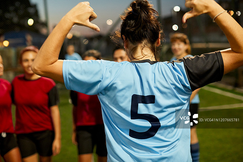 女足球运动员骄傲地指着自己的球衣号码。图片素材