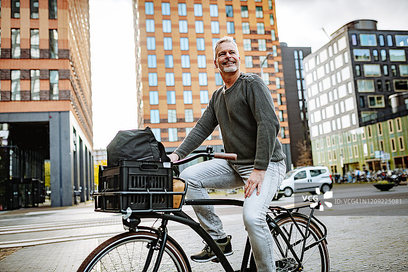 成熟的白发商人骑着自行车，为环保做贡献图片素材