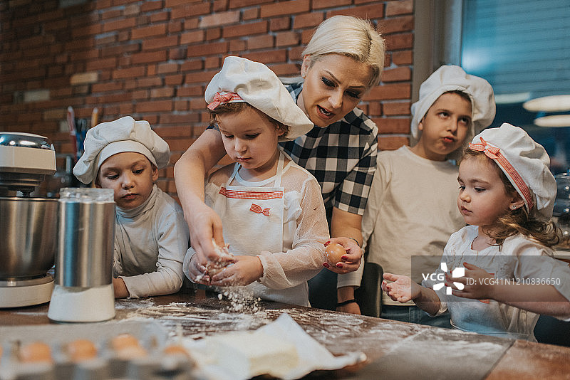 穿着白色厨师服的家庭孩子在厨房里准备食物。图片素材