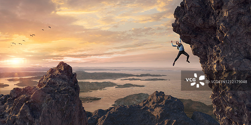 女性极限自由攀登者在日落时攀登陡峭的岩壁图片素材