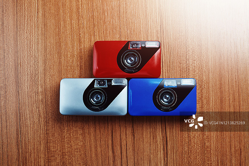 彩色的老式模拟35mm胶片相机彼此并排放置在一张木桌上图片素材