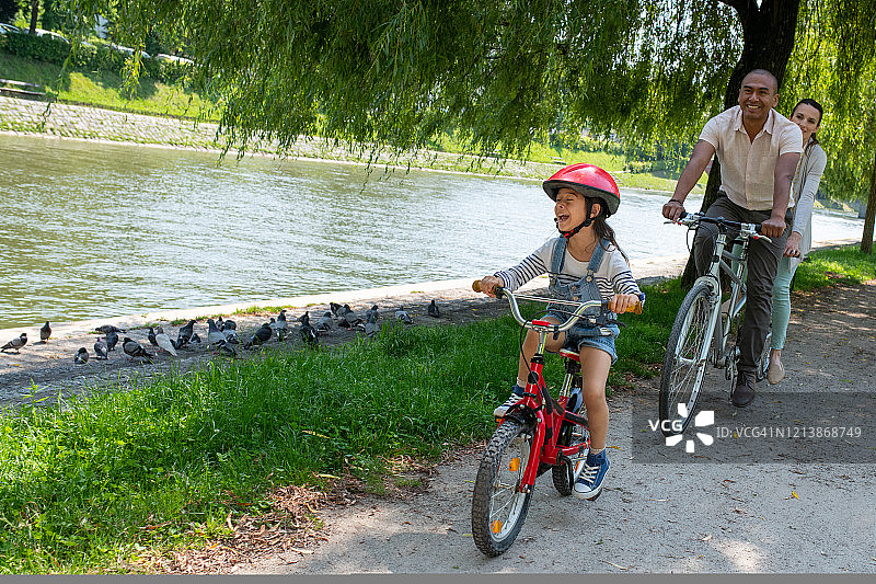 微笑的一家人在河岸上骑着自行车图片素材