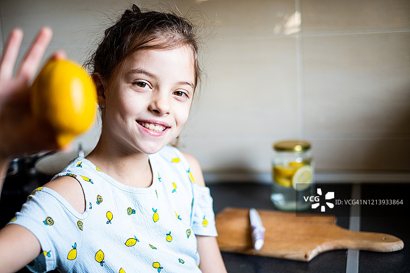 可爱的微笑女孩拿着一个柠檬图片素材