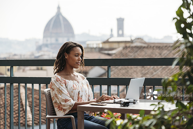 一名年轻女子在意大利佛罗伦萨的阳台上使用笔记本电脑图片素材