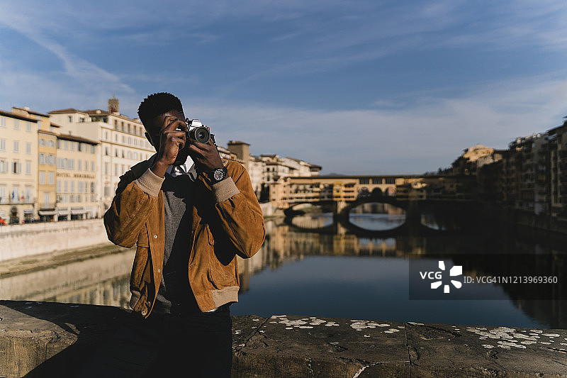 意大利佛罗伦萨，一个年轻人在阿尔诺河上的桥上拍照图片素材