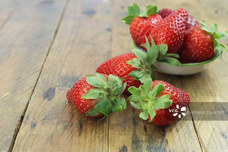 新鲜的有机成熟草莓在一个瓷碗上，在乡村木制背景和复制空间。图片素材