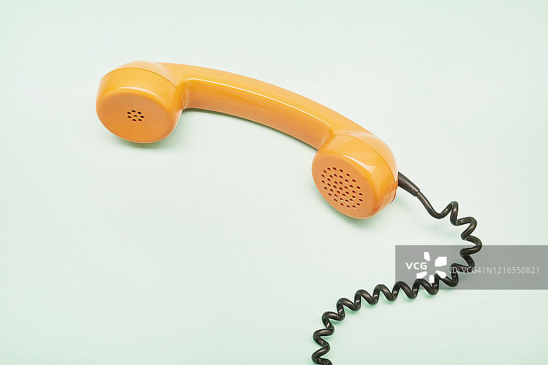高角度的一个橙色的老式电话接收器在绿松石背景图片素材