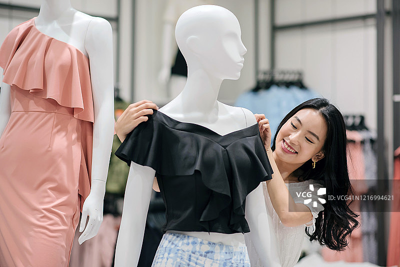 亚洲华人女裁缝在服装店微笑着调整人体模特的衣服图片素材