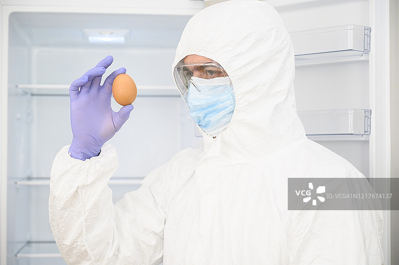科学家在检查一个鸡蛋。他戴着面具、手套和防护服(防护服)。图片素材